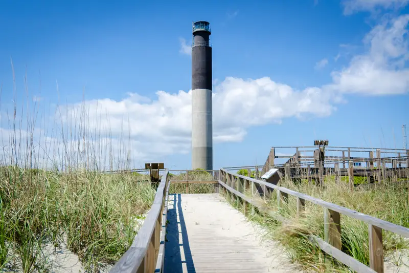 Oak Island Lighthouse seen from a boardwalk through dune grass